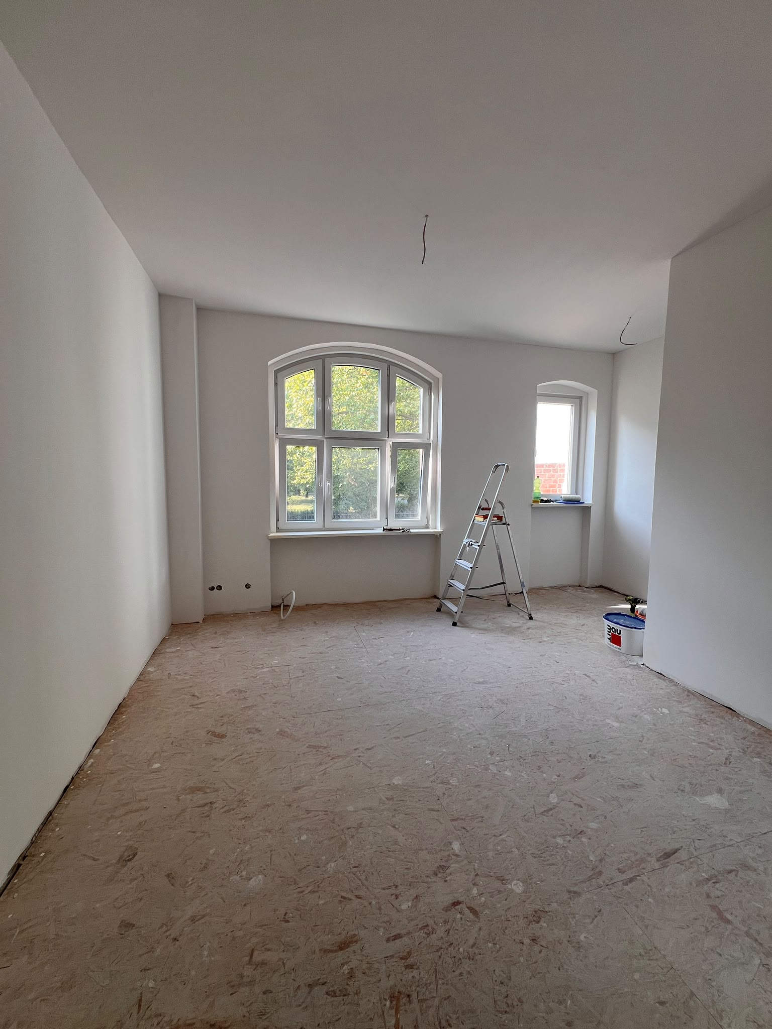 Heller weiß ausgebauter Raum mit Rundbogenfenstern