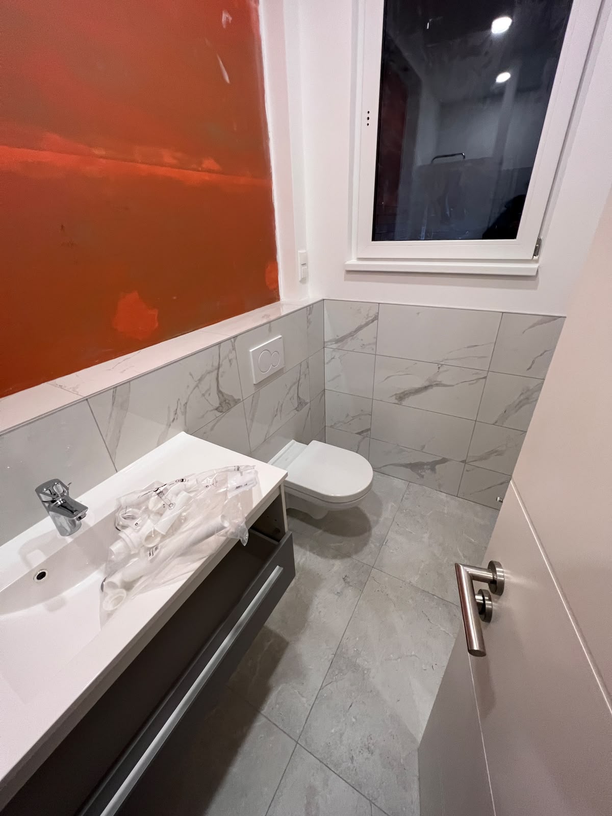 Fertiggestelltes Gäste-WC mit grauen Fliesen
